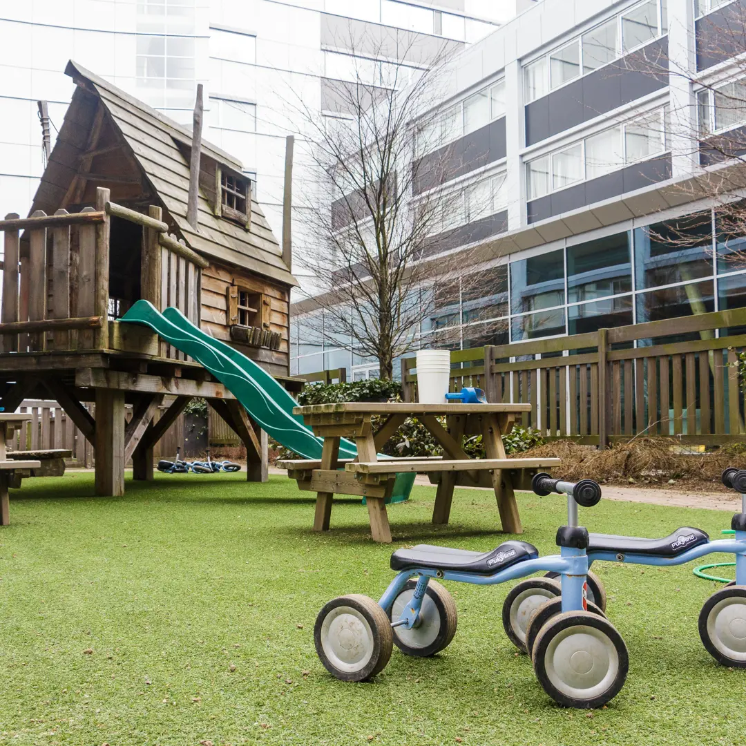 speeltuin kinderopvang met klimtoestel glijbaan fietsjes en picknicktafel