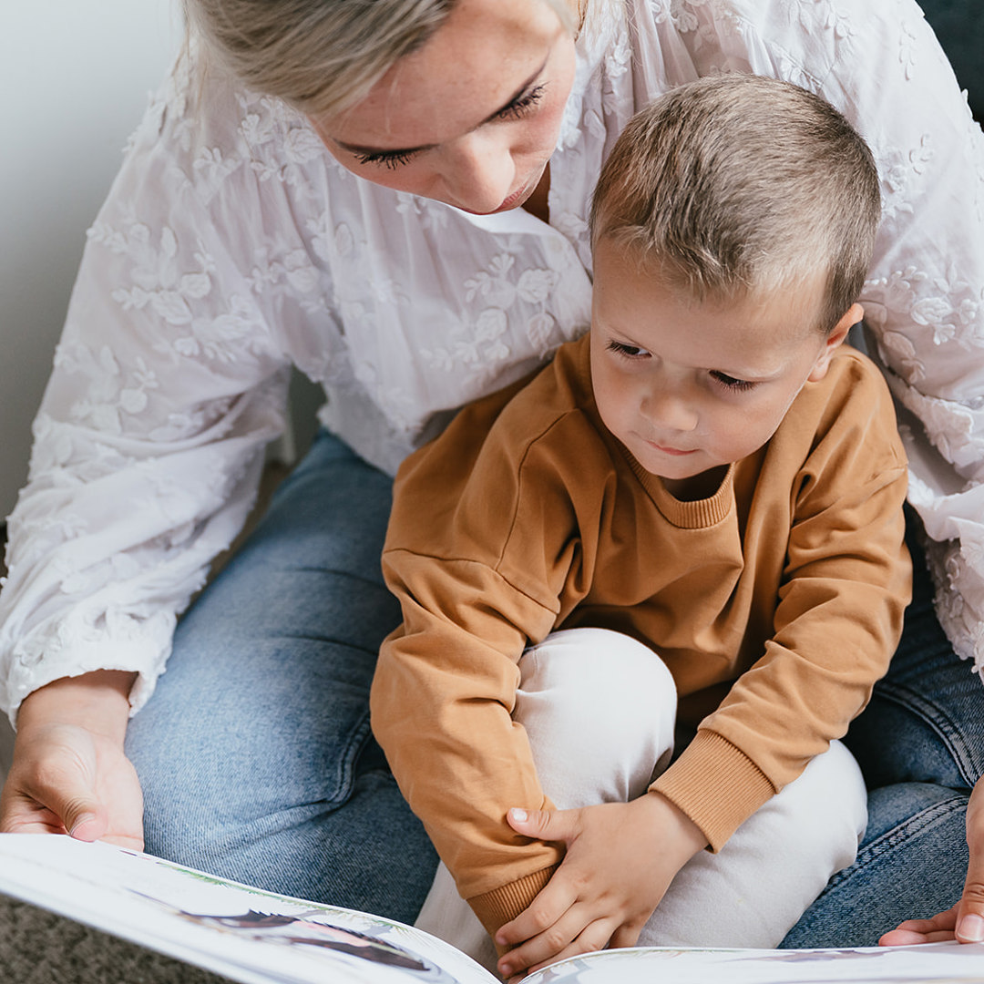 Pedagogisch Medewerker en kind lezen samen een boek